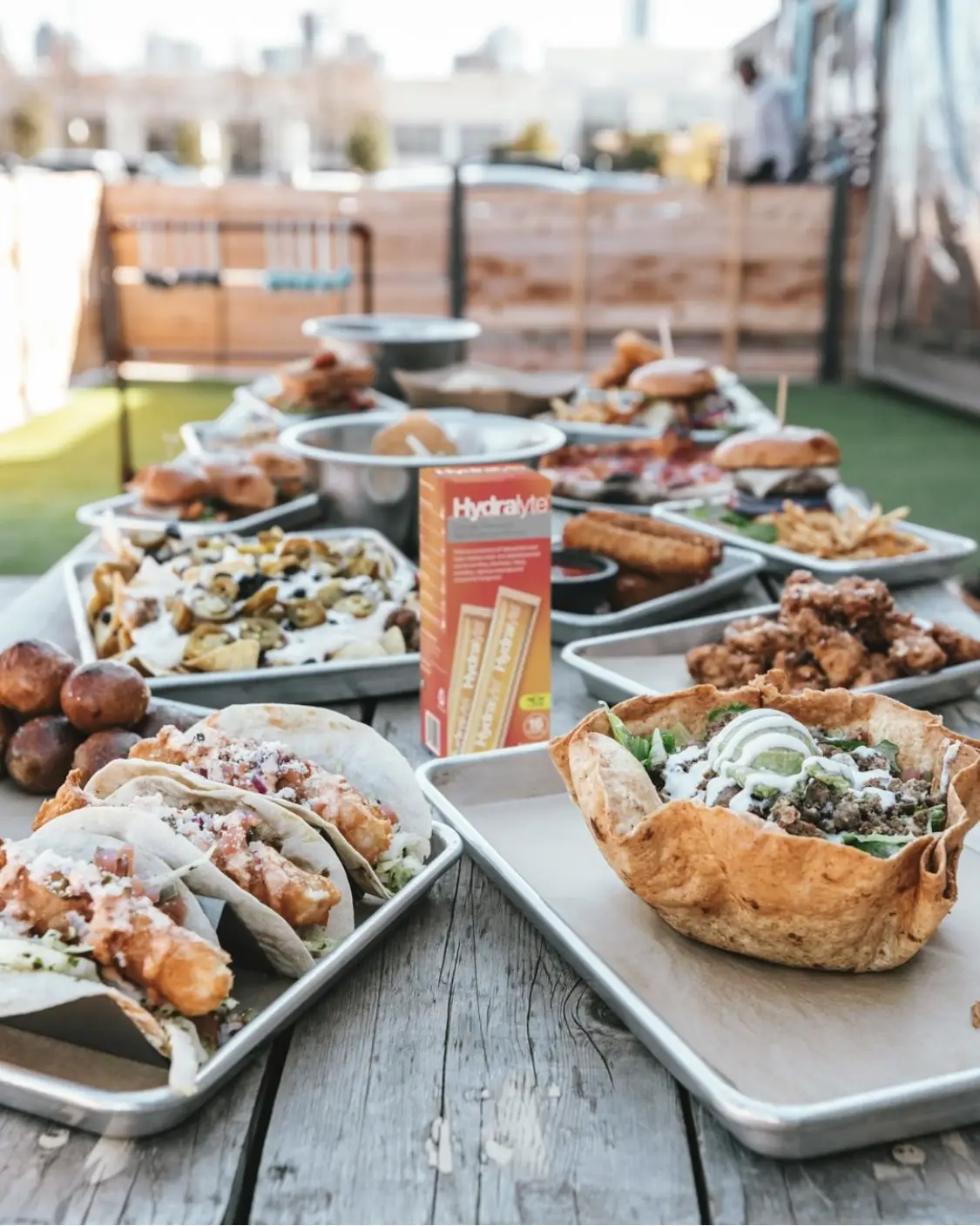 An image of an outdoor dinner table set with food, and a box of Hydralyte iceblocks in the middle of the table.