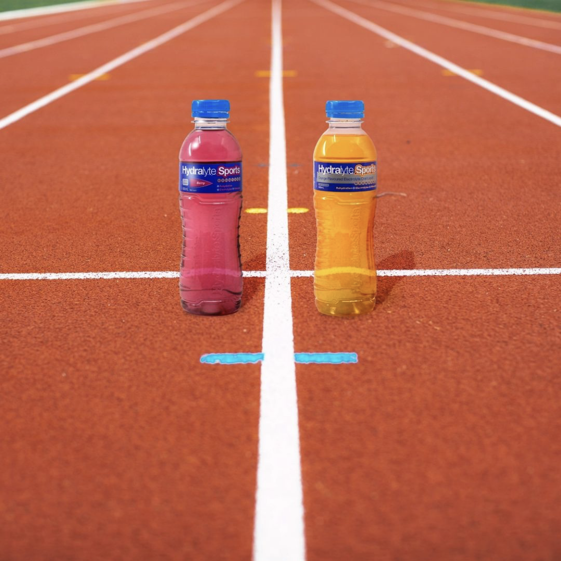 Two bottles of Hydralyte Sports drink on a running track