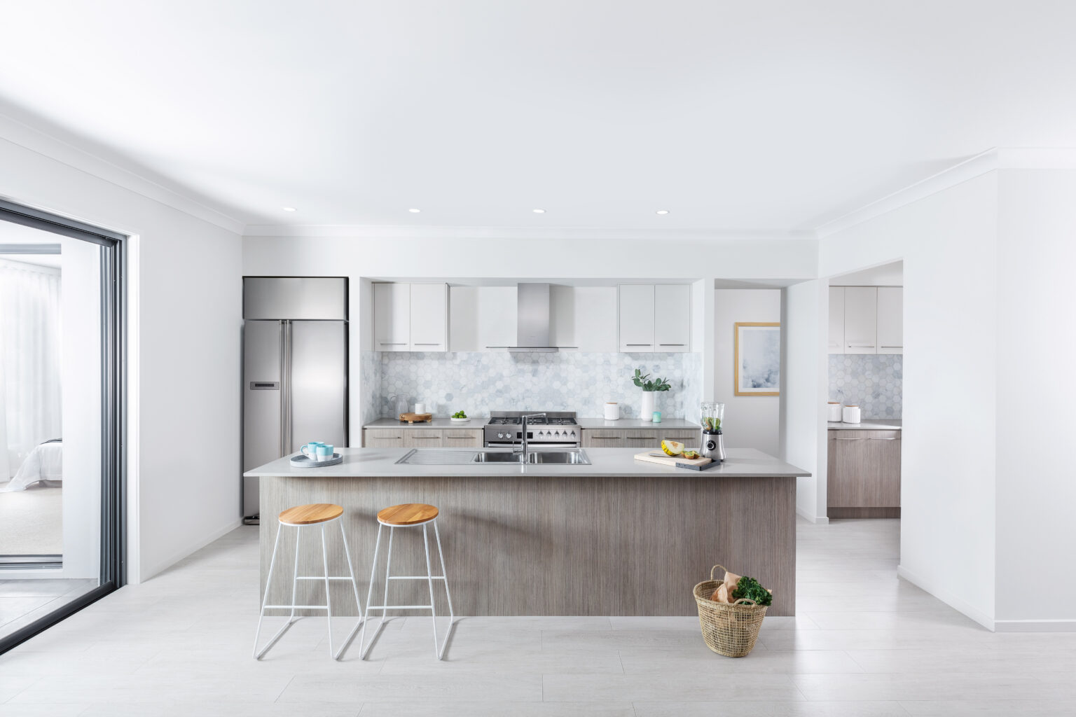 A kitchen in a modern home with white walls, and pale counters and cupboards